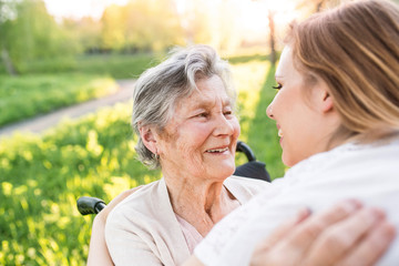 Wall Mural - Elderly grandmother in wheelchair with granddaughter in spring nature.