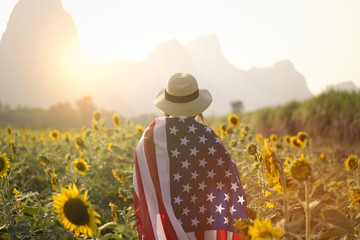 4th July memorial day concept by woman is cover by USA flag in the sunflower field.