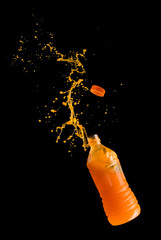 Wall Mural - Orange juice up from a plastic bottle on a black background,orange juice splash