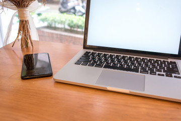 Computer notebook and flower with a coffee shop behind the scenes Blur Coffee shop, Blur restaurant sun flare effect photo.