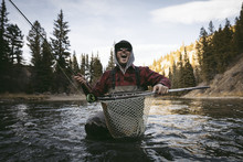 Cheerful Man Screaming While Fishing In River Against Sky At Forest