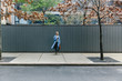 © Cavan Images - Young woman standing against shutter corrugated galvanized iron at sidewalk