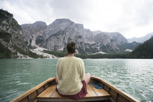 Rear View Of Woman Sitting In Boat On River Against Mountain