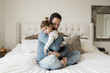 © Cavan Images - Portrait of sad daughter embraced by father on bed at home