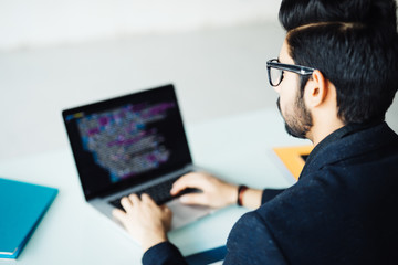 Indian software developer working on laptop at his office table