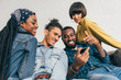 © LIGHTFIELD STUDIOS - young black man pointing at smartphone screen to smiling friends