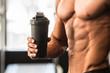 © Nick Starichenko - Man with perfect body holds protein shaker in the gym after workout