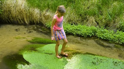 child cute blond girl playing in the creek. summer children fun.