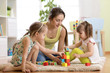 © Oksana Kuzmina - Family activities in the children room. Mother and her kids daughters sitting on the foor and playing.