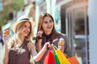 © Mediteraneo - Happy young women with shopping bags and ice cream having fun on city street