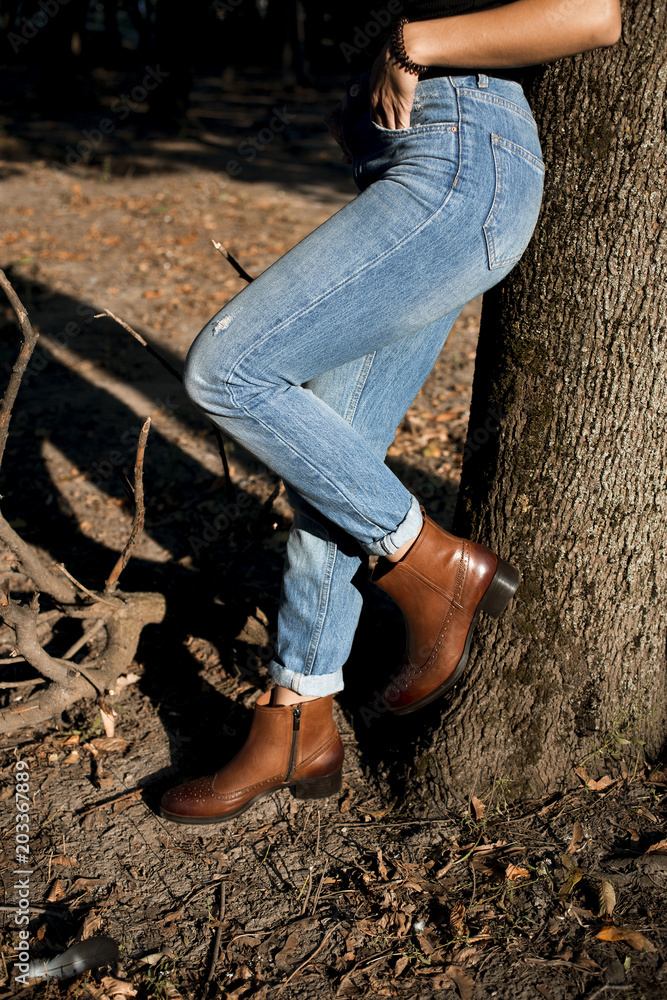 Brown shiny leather womens chelsea boots on woman legs with blue jeans in autumn forest or park. Stock Photo | Adobe Stock Brown shiny leather womens chelsea boots on woman legs with blue jeans in autumn forest or park. Stock Photo | Adobe Stock