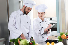Professional Team Of Cooks Checking Recipe During Cooking Dish