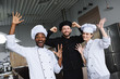 © LIGHTFIELD STUDIOS - smiling multicultural chefs having fun at restaurant kitchen