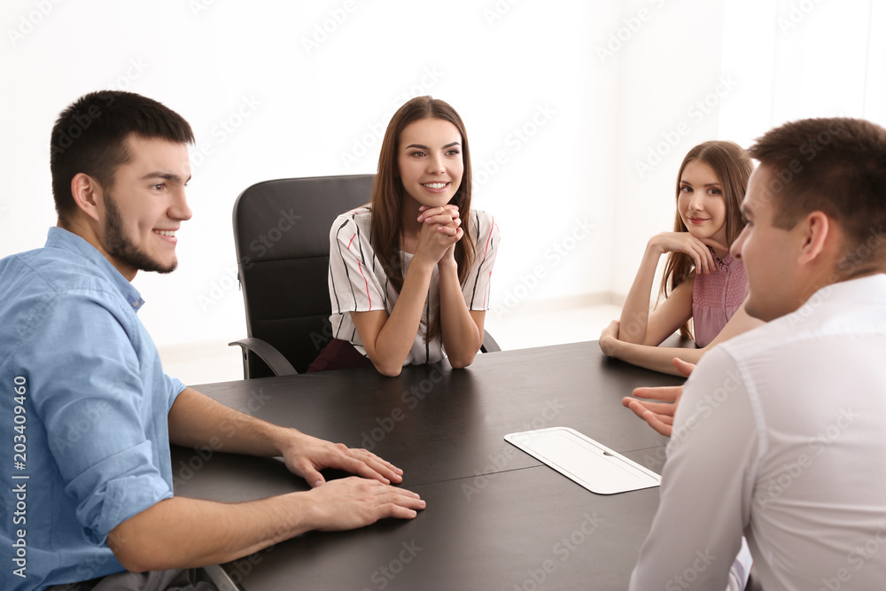 Young people sitting together at table, indoors. Unity concept