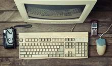 Retro Stationary Computer On A Rustic Wooden Desk, Vintage Workspace. Monitor, Keyboard, Computer Mouse, Top View, Flat Lay.