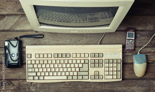 Plakat Retro stationary computer on a rustic wooden desk, vintage workspace. Monitor, keyboard, computer mouse, top view, flat lay.