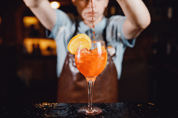 Close-up of barman mixes cocktail with ice orange, whiskey, liquor.