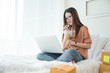 © Shutter2U - Beauty Asian woman using laptop and drinking coffee on bed. Business and Technology concept. Delivery and Online shopping concept. Post and Service theme.
