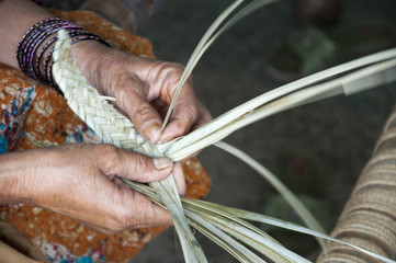 Woman weaving with date palm leaves in in the village