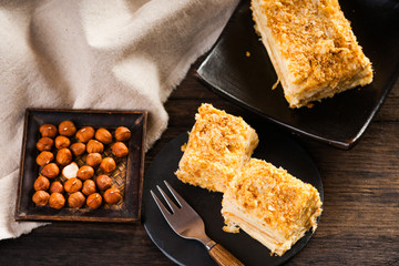 Wall Mural - Slices of sweet classic layered cake Napoleon, fork and hazelnuts 