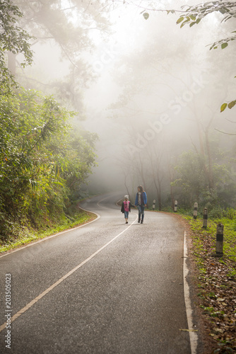 Fotografia, Obraz A little girl and mother run on a road in the forest