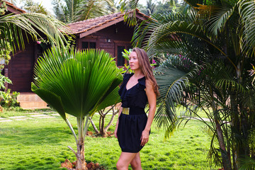 Wall Mural - Tanned girl on the background of a palm forest.