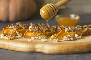 Wall Mural - Authentic view of a pumpkin baked with slices of honey and walnuts on a wooden kitchen board.