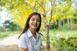 © arjan_ard_studio - portrait of the happy beautiful Thai student with university uniform standing and smiling on the yellow tree background