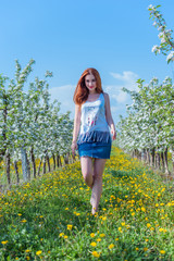 Beautiful girl in apple blossom garden on a spring day. Summer romantic image of stylish casual woman in t shirt and jeans skirt , trendy and fashionable accessories . positive mood 