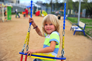 Joyful boy swinging outdoors, summer scene