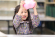 © Nattanon - Happy kids Playing and raised a Pink Saving Pig Jar in the Library. Setup studio shooting.