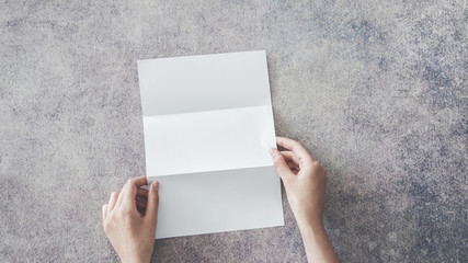 Wall Mural - Female hands holding blank white folded paper on background