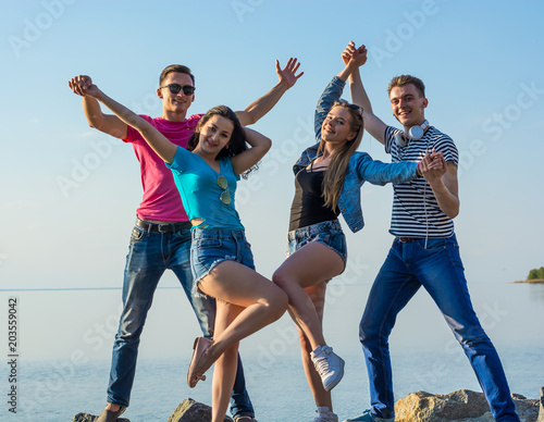 Fotografia Friends are have fun and dancing along on a seashore, holding hands and laughing