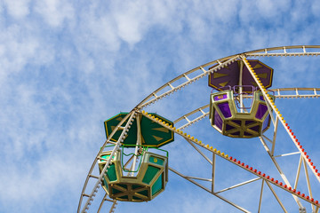 Colorful ferris wheel against blue sky as background. Two cabins ferris wheel close up