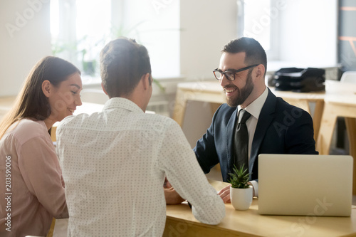 Cuadros en Lienzo Friendly lawyer or financial advisor in suit consulting young couple, smiling in