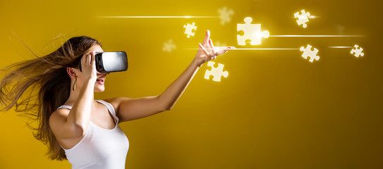 Wall Mural - Puzzle Pieces with young woman using a virtual reality headset