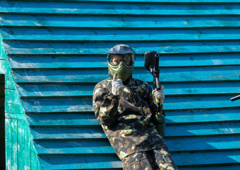 Wall Mural - Boy in camouflage suit stands on the paintball field with his paintball gun up and looks straight ahead. team work, sport lifestyle