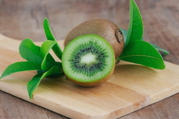 Wall Mural - Fresh and juicy kiwi fruit and a half on cutting board on wood table in side view with copy space for background or wallpaper. Kiwi have sweet and sour taste and have high vitamin c and antioxidant.