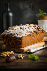 Sweet cake baked  with dates, nuts and sprinkled with powdered sugar on the brown wooden table.