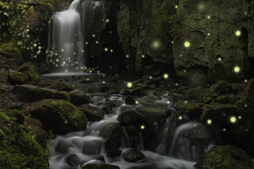 Beautiful fantasy image of fireflies over stream in rocky canyon landscape at dusk