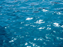 Water Surface. Abstract Background, Seawater In Sunlight. Summer Background. Sunlight Bokeh Sparkles Deep Turquoise Water Mediterranean Sea Blurry Background