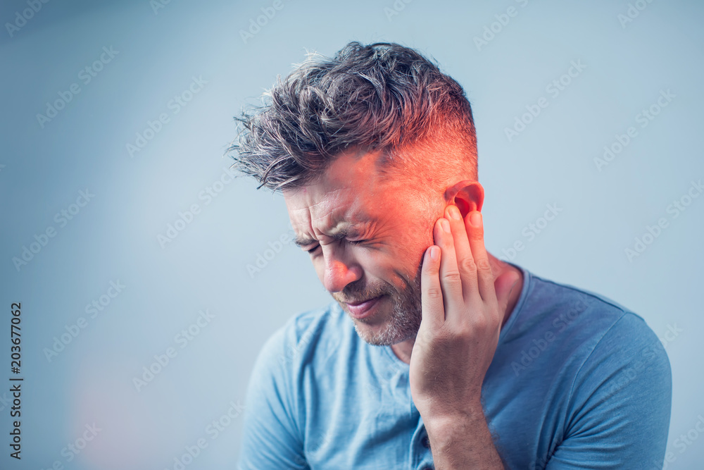 male having ear pain touching his painful head isolated on gray background - obrazy, fototapety, plakaty 