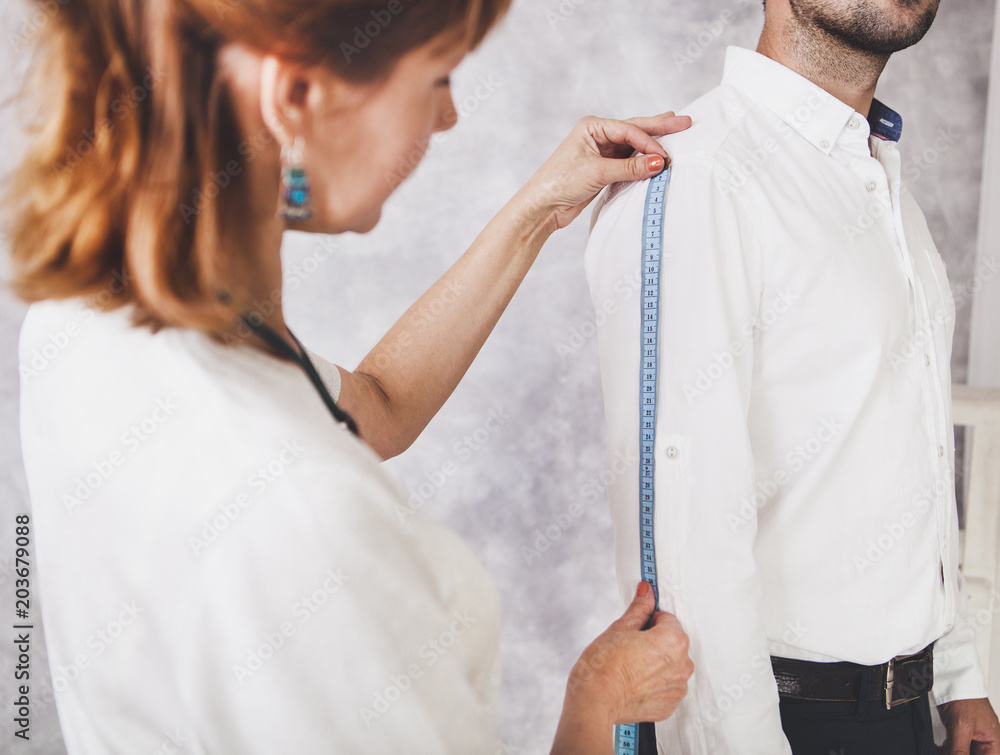 Woman tailor takes measures with male models. Fashion designer sews a ...