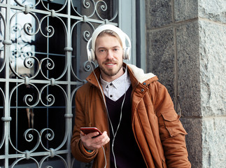 Canvas Print - Portrait of handsome hipster with headphones listening to music outdoors