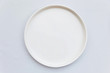Top view of white empty plate on white tablecloth.