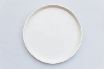 top view of white empty plate on white tablecloth.