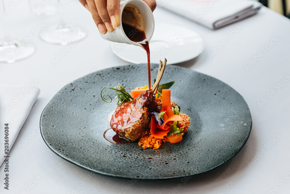 Modern French cuisine: Roasted Lamb neck & rack served with carrot, yellow curry pouring lamb sauce. Served in black stone plate - obrazy, fototapety, plakaty 