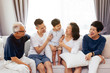 Happy Asian extended family sitting on sofa together, posing for group photos