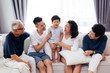 © twinsterphoto - Happy Asian extended family sitting on sofa together, posing for group photos