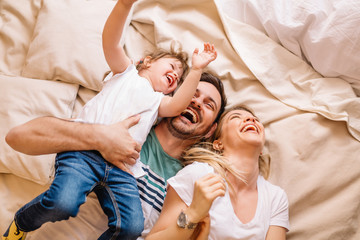 happy family having fun in the bedroom while they lie on bed